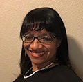 Deborah smiling at camera with blank wall behind her