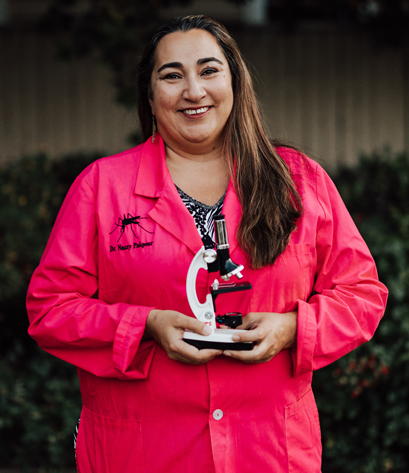 Nazzy Pakpour poses in hot pink lab coat holding a microscope 