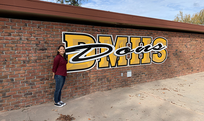 Person standing next to painted brick wall