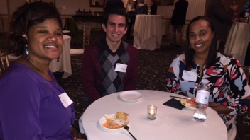 Three Aggies at a round table smiling 