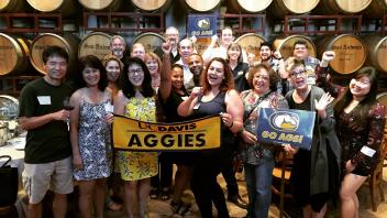 Group of Aggies in front of barrels of wine 