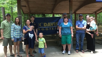 Group of Aggies standing next to UCD flag 