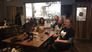 Six Aggies sitting at a table smiling 