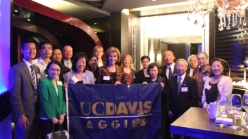 Group of Aggies standing with UC Davis flag 