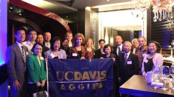 Group of Aggies standing with UC Davis flag 