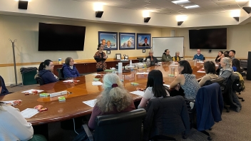 A group of people gathered around the conference room table at the Founders Board Room at the Alumni Center for a tea tasting and demonstration.