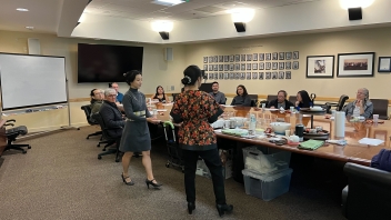 A group of people gathered around the conference room table at the Founders Board Room at the Alumni Center for a tea tasting and demonstration.