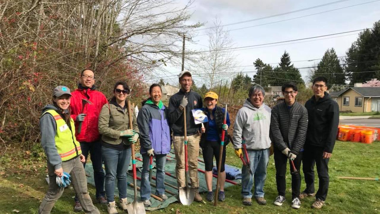 A group of UC Davis alumni in Seattle at a community service day posing with shovels outdoors