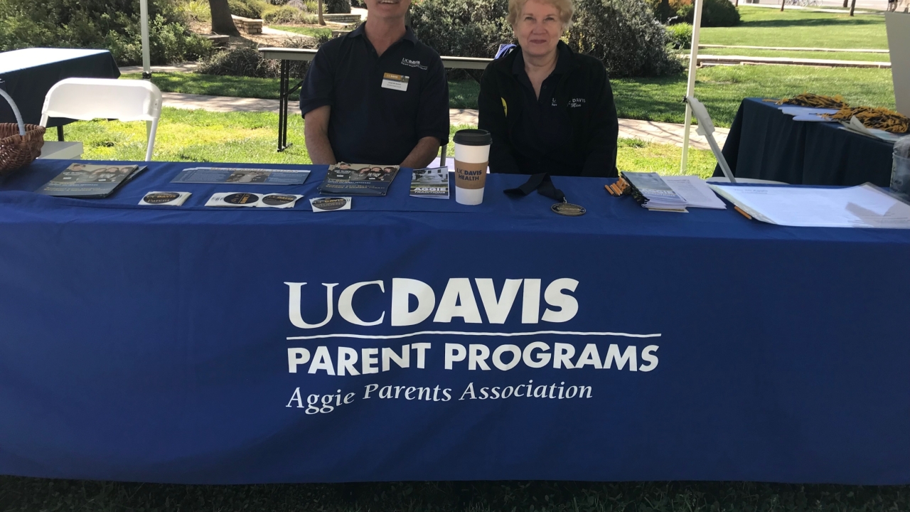 Two people sitting at a table with a sign that says UC Davis Parents Program