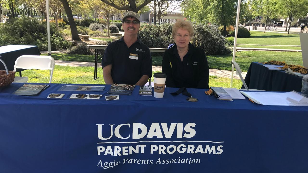 Two people sitting at a table with a sign that says UC Davis Parents Program