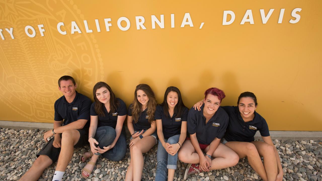 Students sitting in front of a UC Davis sign