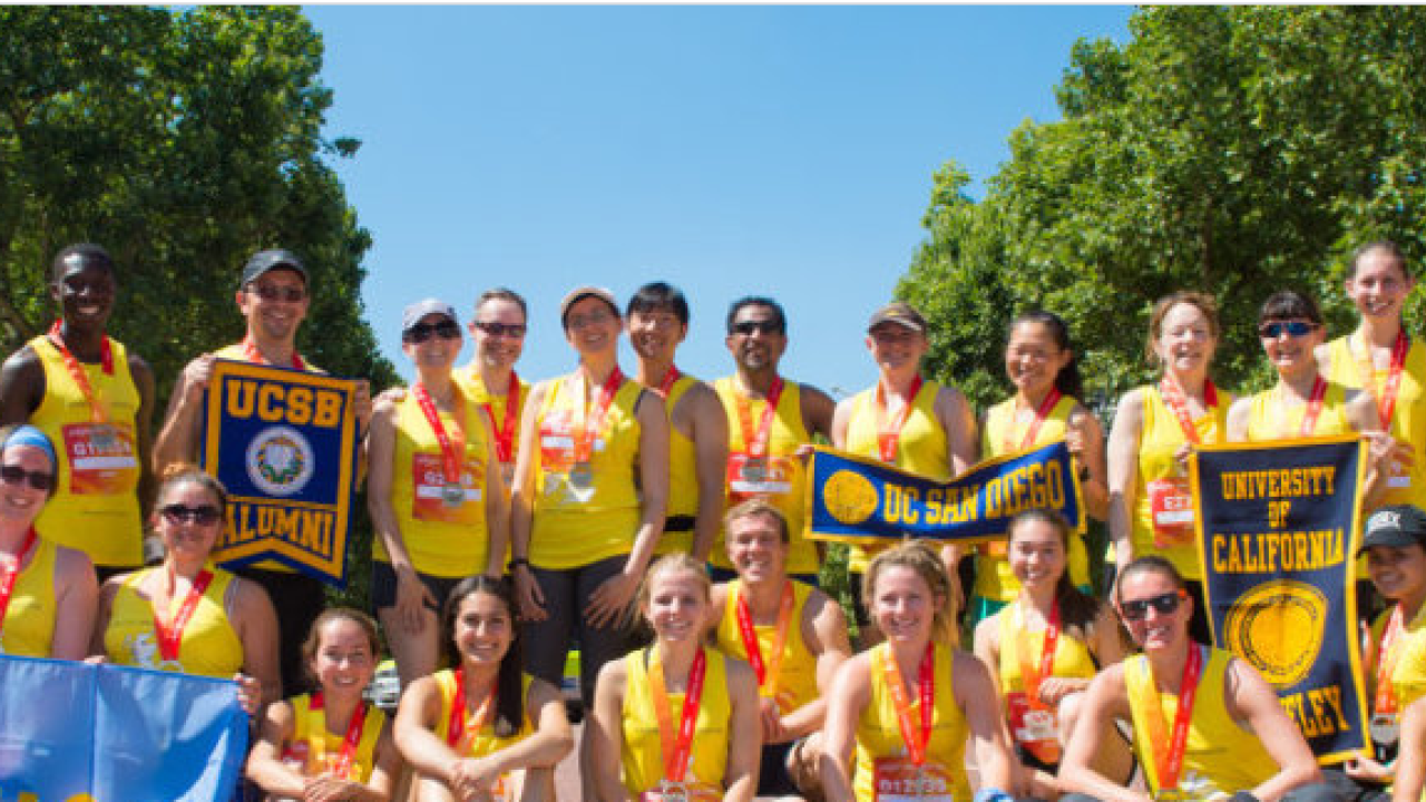 Group photo of UC alumni in yellow shirts with medals on after the Vitality race.