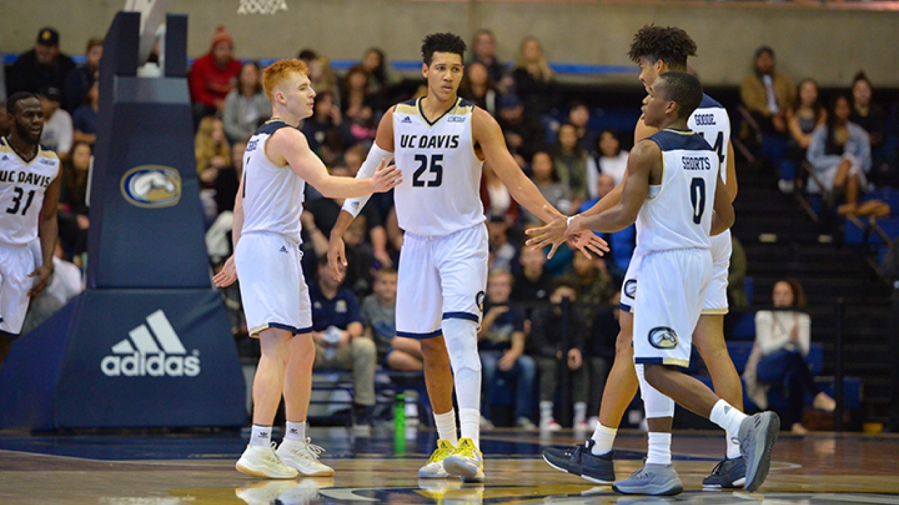 Men's basketball team on court giving high-fives