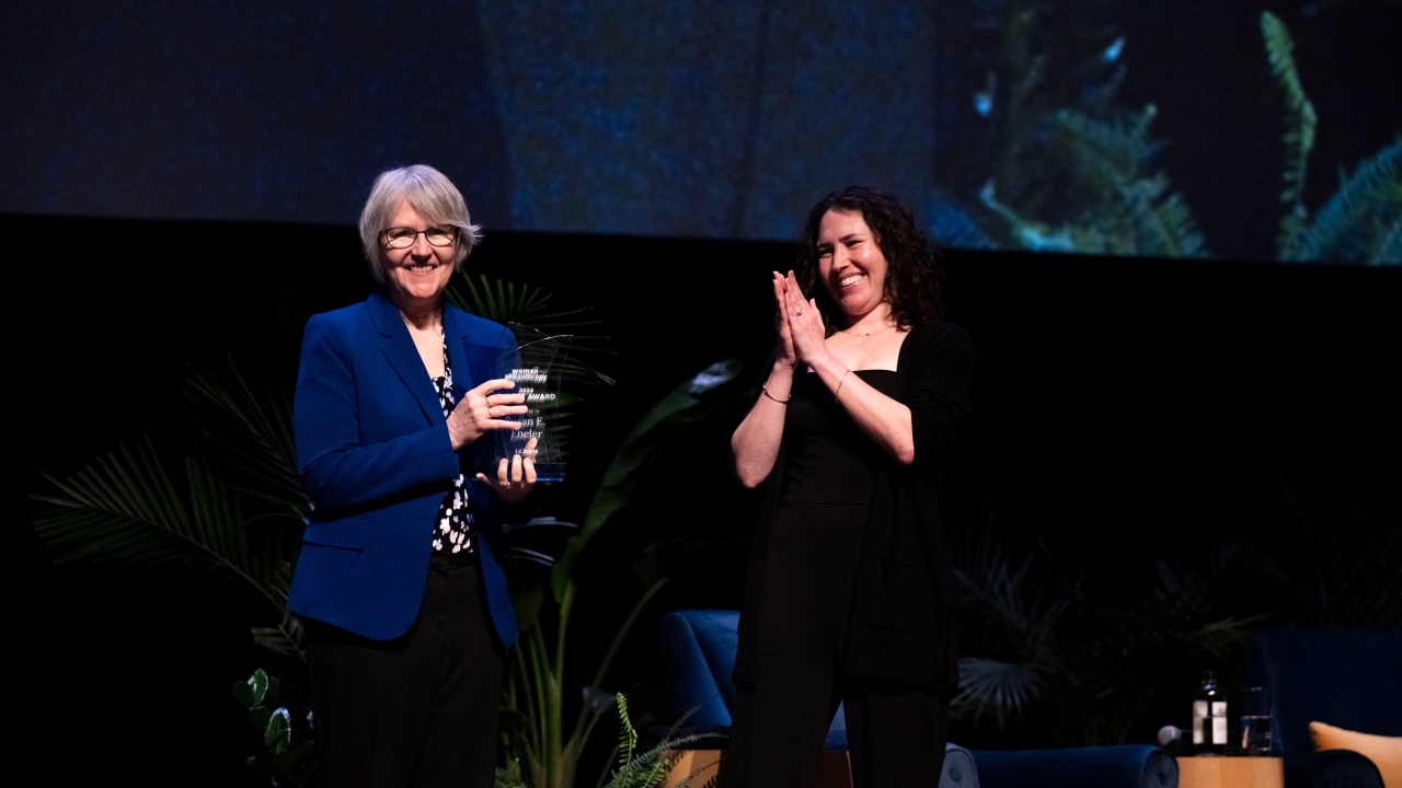 Sue Ebeler being presented with the Women & Philanthropy Impact Award on stage by Kelli Brown.