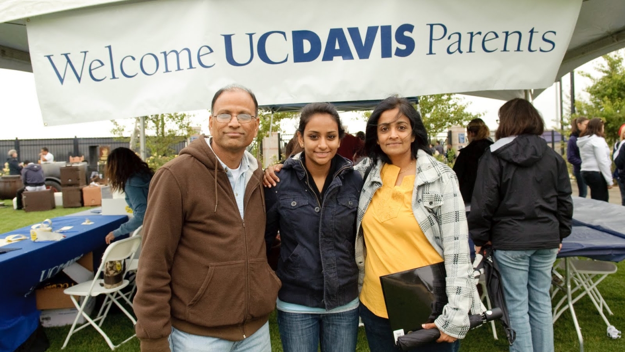 Image of three people in front of a Welcome UC Davis Parents sign