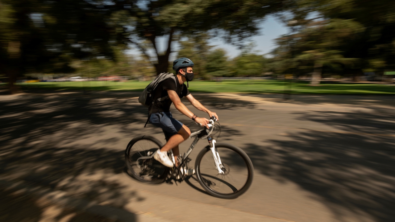 student riding on a bike on campus