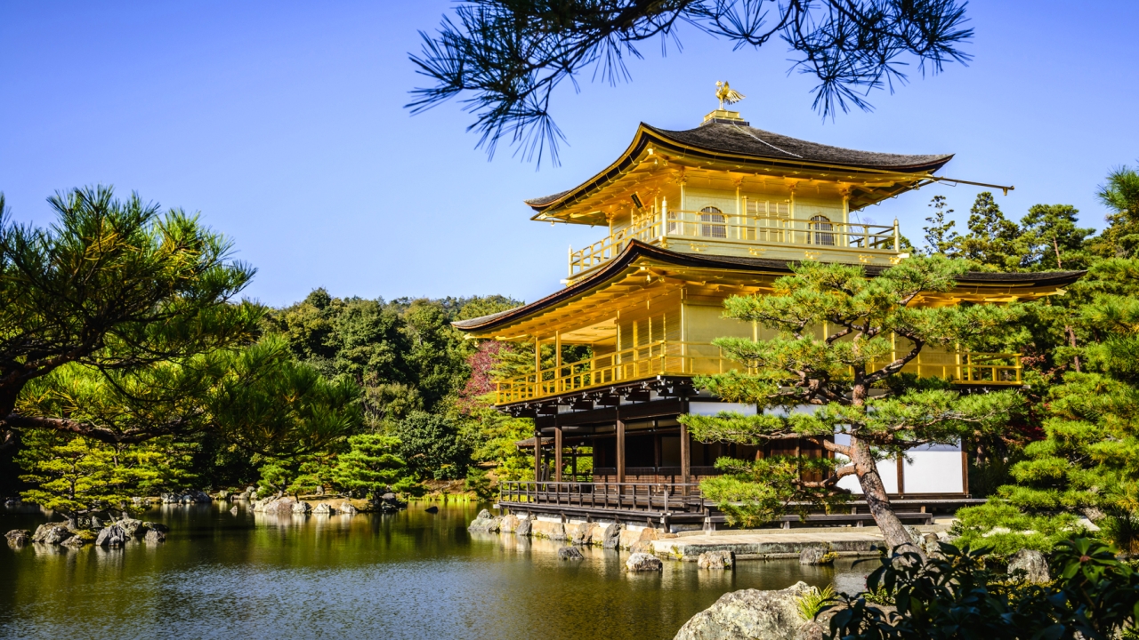 A beautiful shrine surrounded by Japanese pines sits by a peaceful lake.