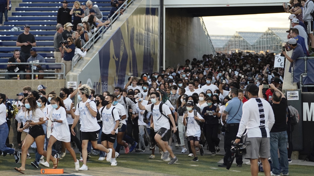 UC Davis students running onto the Aggie football field