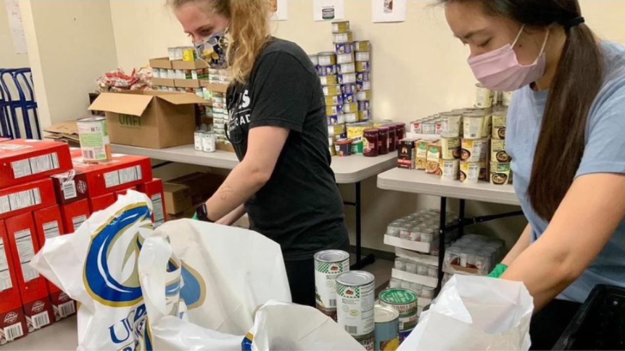 Two UC Davis students stuff groceries into bags at the student pantry.