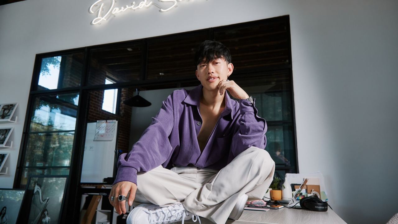 David Suh sitting on a desk at his studio in L.A.