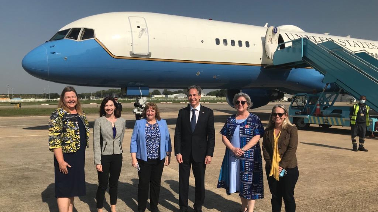  A group of people stand in front of a blue and white plane on the runway.