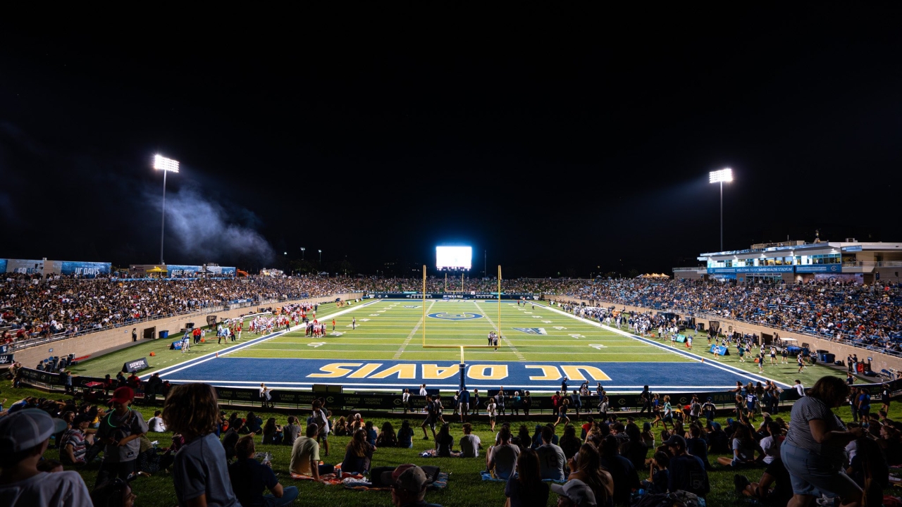 View of UC Davis Health from the endzone looking down the field during a night football game