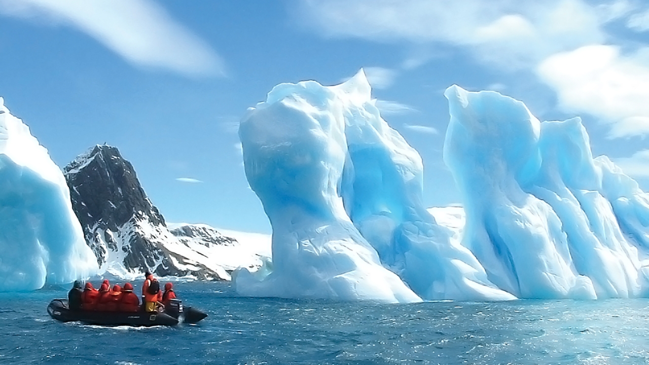 Aggie Travel members aboard a Zodiac craft observe the floating ice sculptures on the water's surface.