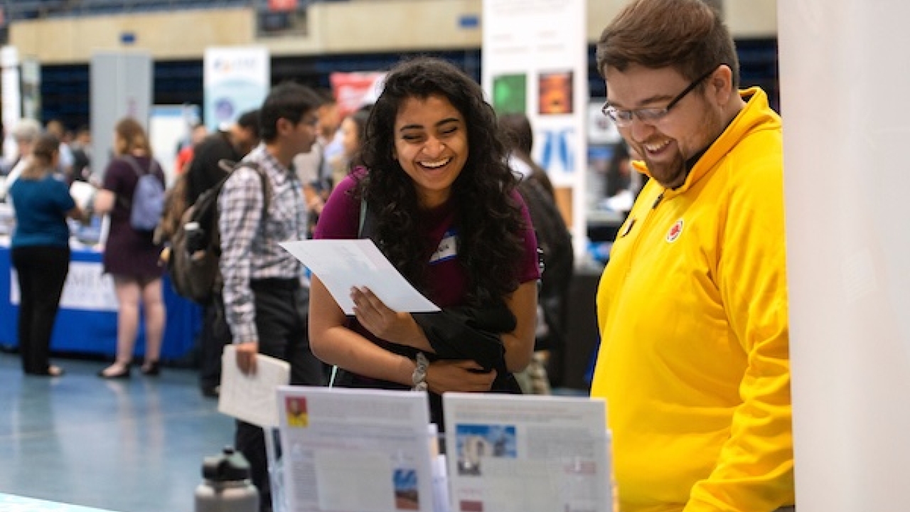 two students standing at a table looking at career information sheets