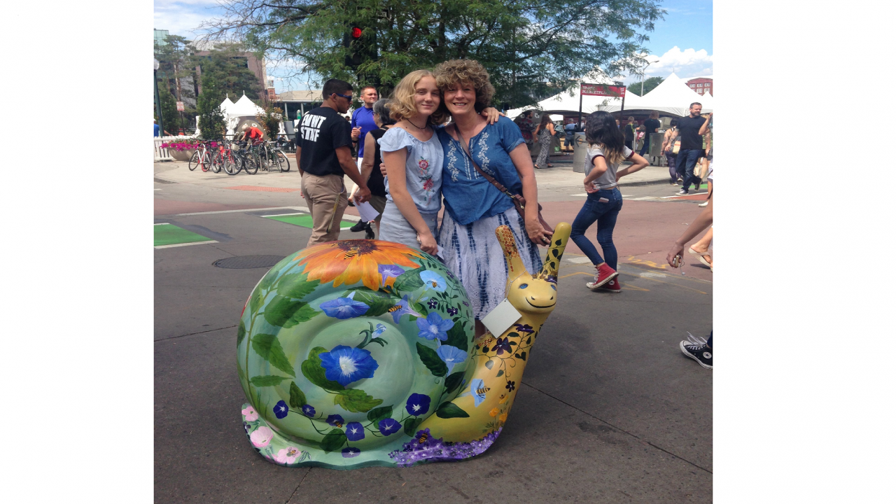 Picture of orinne Bourdeau and daughter Michaela Koski ’23 attending a Slow Food conference. They are standing next to a giant snail sculpture. 