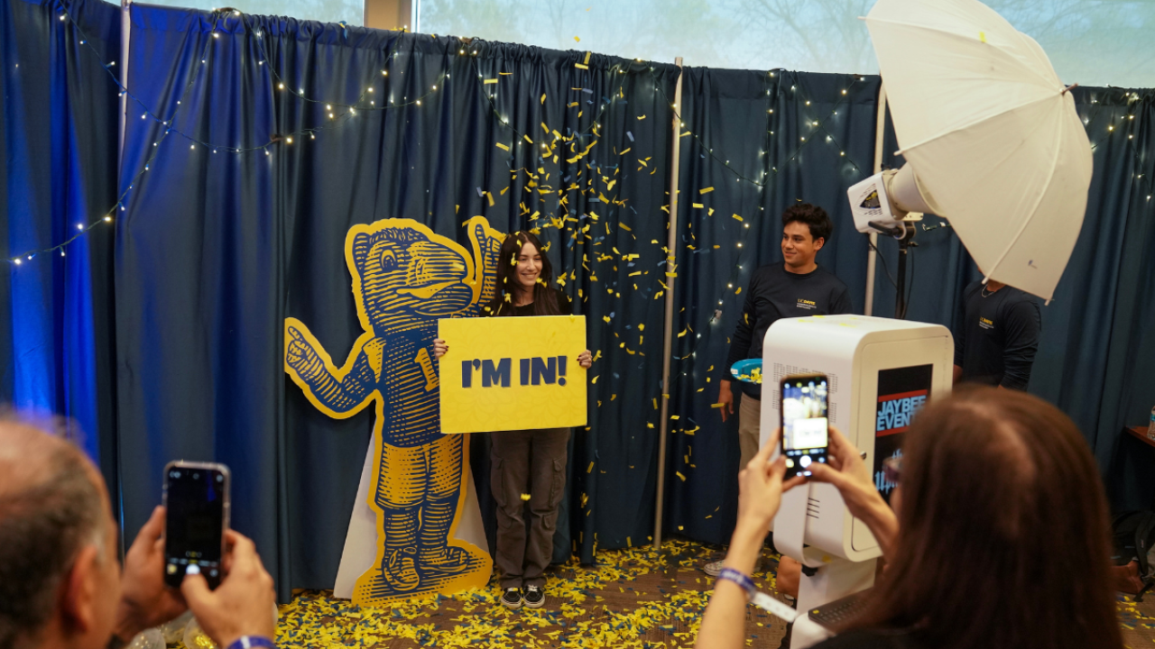 Student taking photo with Gunrock cutout holding "I'm In!" sign