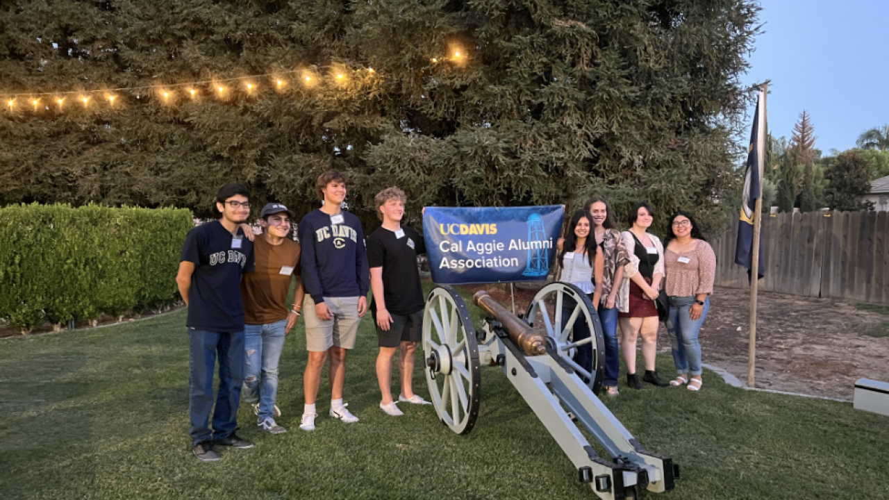 Students around a cannon with a Cal Aggie Alumni Association banner on it