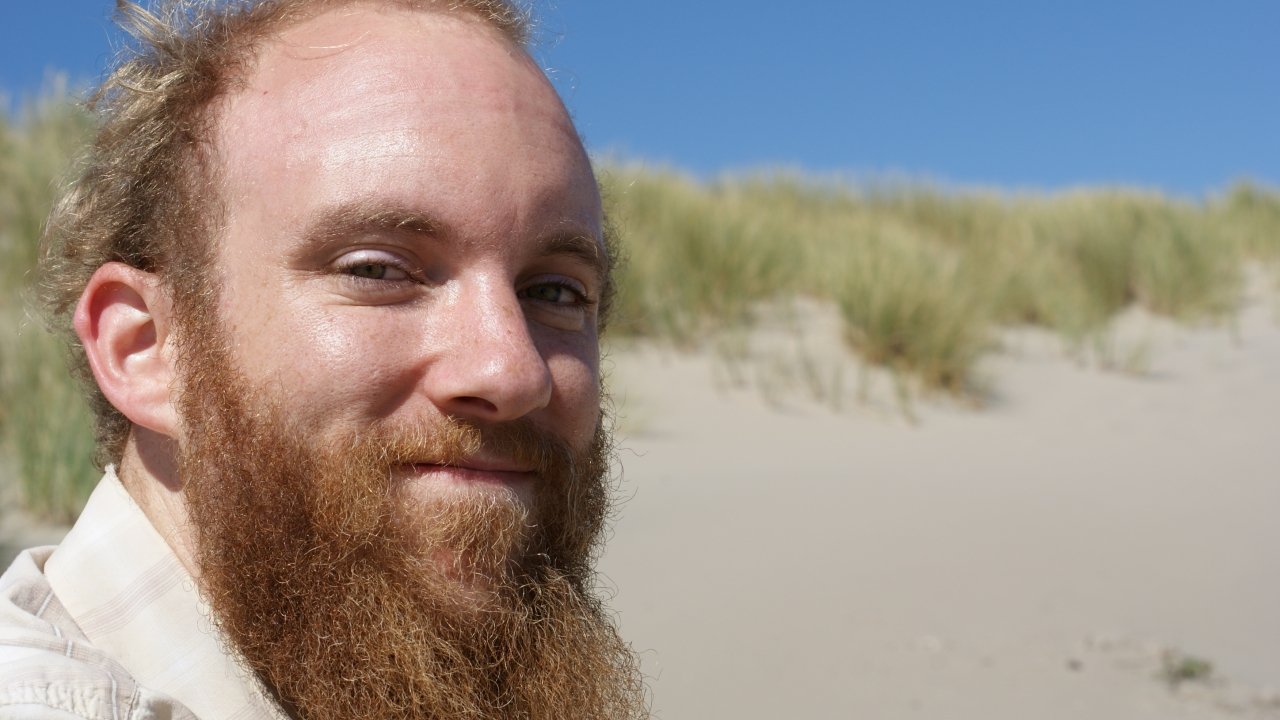 Lewis Lawyer smiling with sand dune in background.