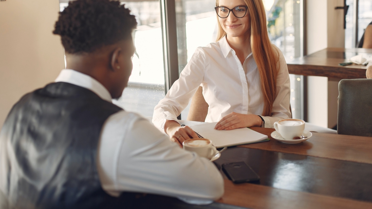 image of a women interviewing a man, he is dressed in business professional attire