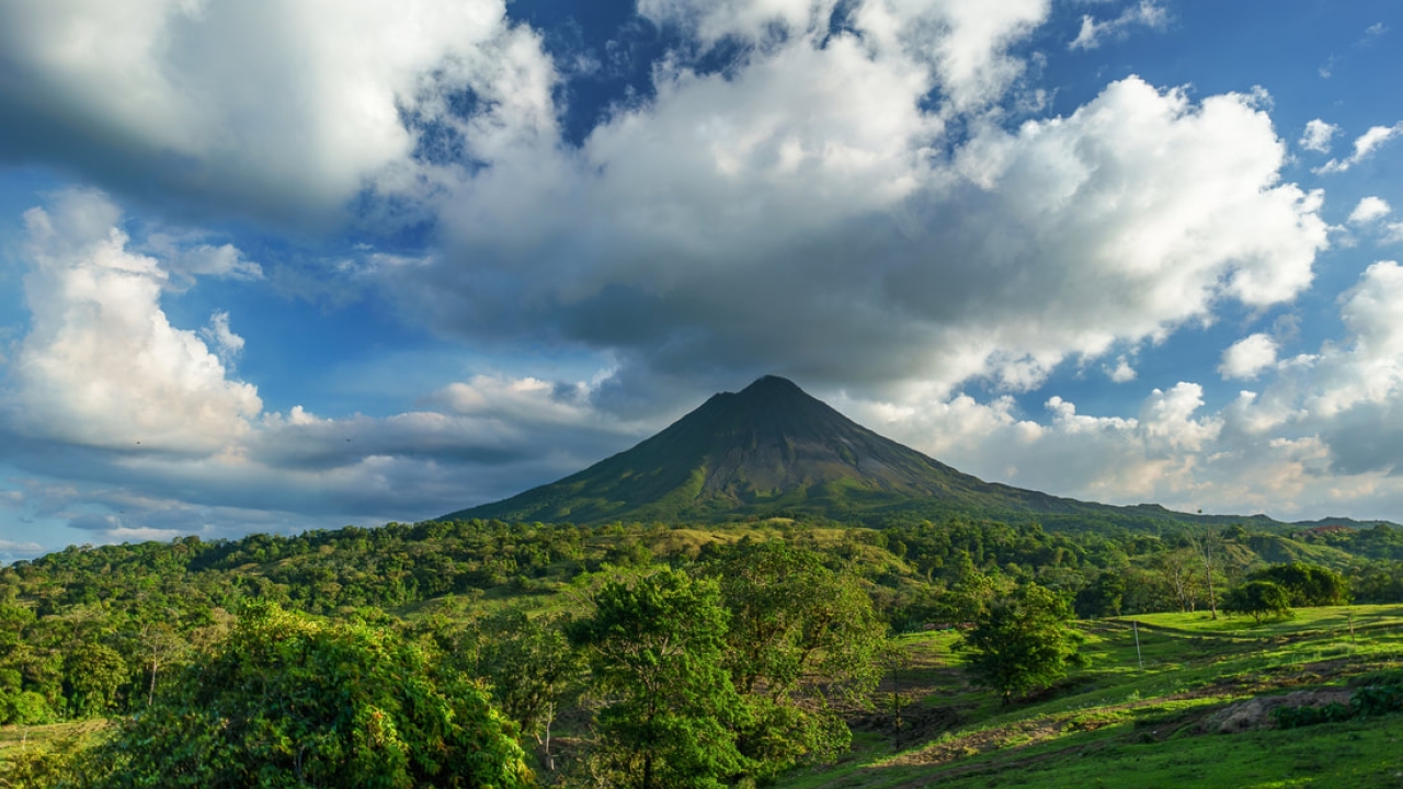 Lush green landscape with volcano and clouds