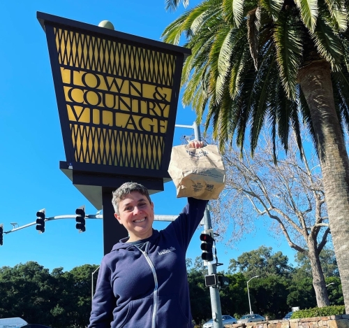 Emily holding a bag of bagels in front of her Palo Alto store.