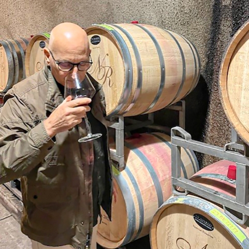 David Llodra sampling wine at Nicholson Ranch with several wine barrels visible.