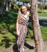 Anya Nygaard leaning against a tree wearing a striped dress.