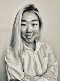 Picture of Estee Kim wearing a button-up shirt, smiling and looking at the camera.