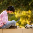 student sitting outdoors with laptop