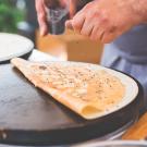 Picture of someones hands making crepes.