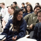 photo of a classroom at UC Davis. Students are seated in a lecture style room and the photo is focused on two students facing each other and conversing