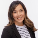 Headshot of Brea Aguas posing in a striped shirt and black blazer.
