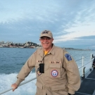 David Holcombe leaning on the rails on the side of a boat with his hand.