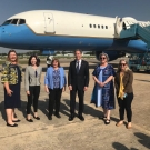  A group of people stand in front of a blue and white plane on the runway.