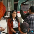 An actor in a white blouse and red cardigan is surrounded by a film crew while shooting the feature film, Kintsukuroi, in September 2022. 
