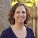Headshot of Julie Nico Martin in a purple blouse in front of a tree outdoors.