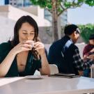 Brandy drinking cup of coffee at table outdoors