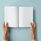 Hands holding open a book with empty pages