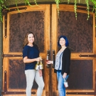 Shaina Harding and NC pose in front of door holding wine bottles