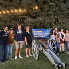 Students around a cannon with a Cal Aggie Alumni Association banner on it
